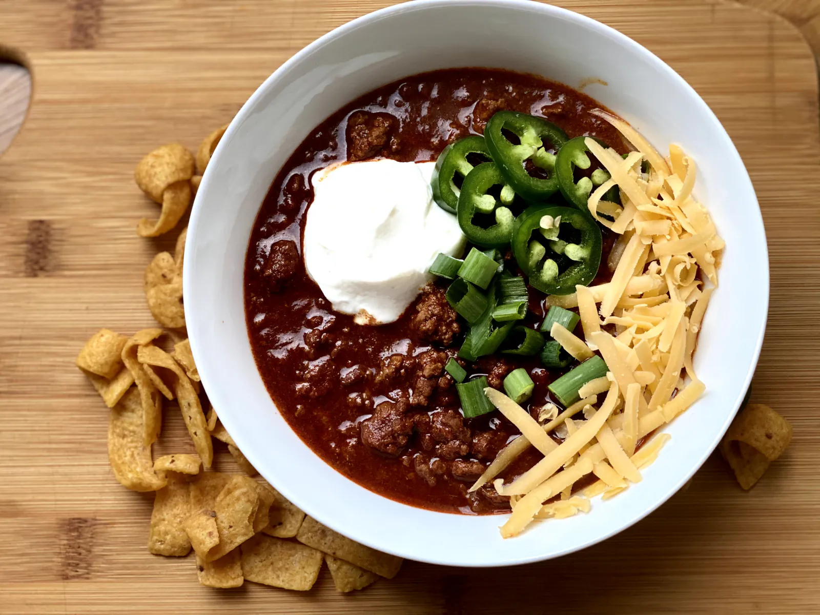 A finished bowl of Pecos Red chili with sour cream, jalapeños, and cheddar